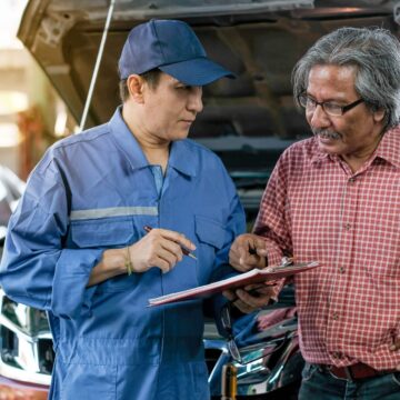 garagiste-problem Un mécanicien automobile asiatique en uniforme bleu explique les listes de problèmes de la voiture au client dans le garage.