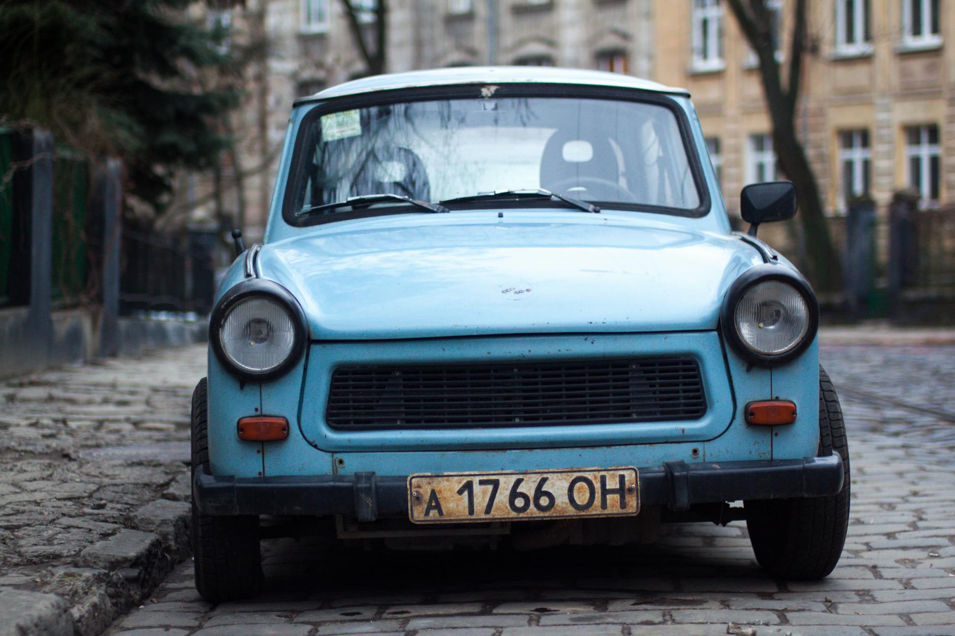 Voiture bleue classique garée près d'une clôture et d'arbres