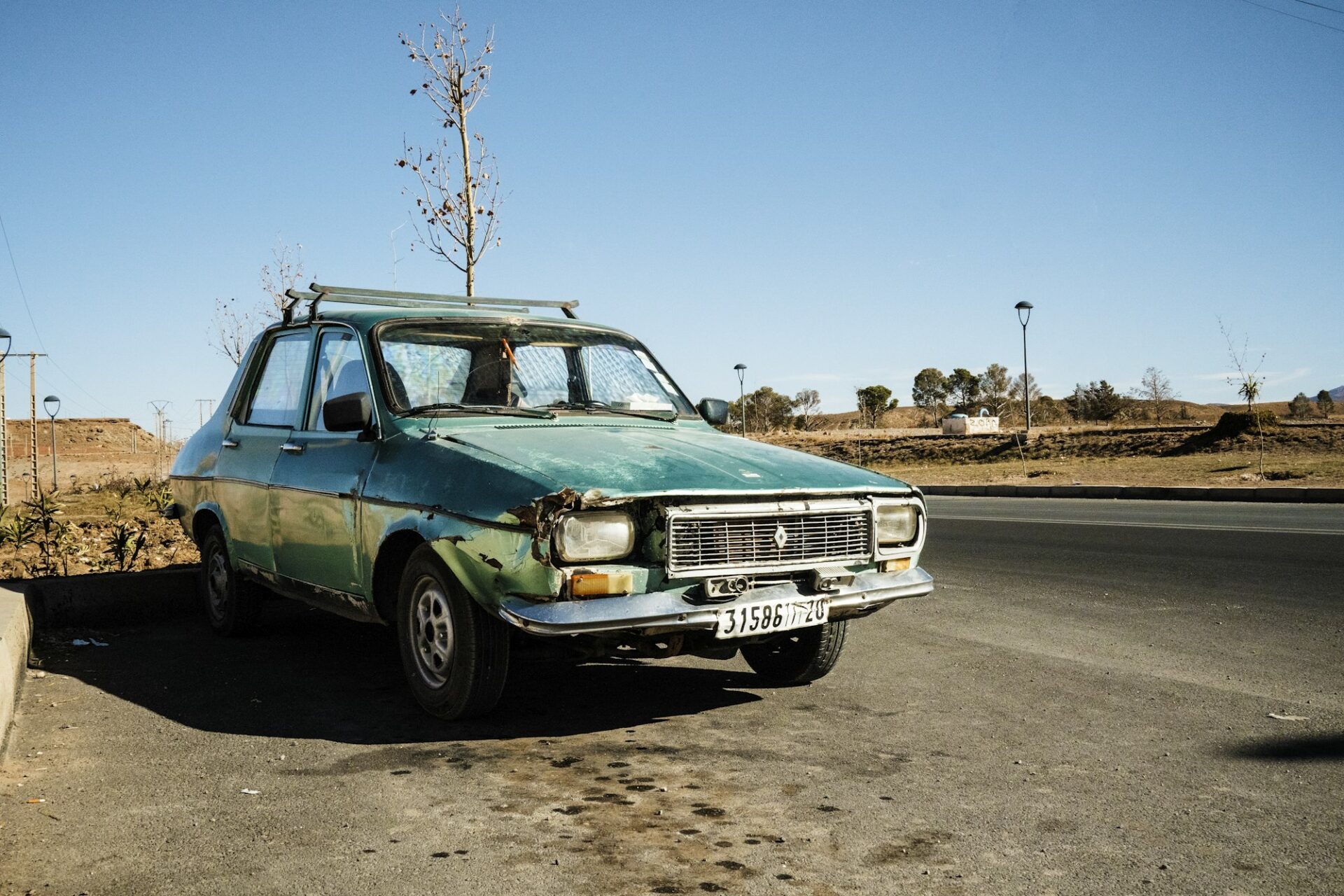 Marrakech, Maroc - 31 décembre 2017 : Vieille voiture verte détruite et grungy garée au bord de la route en milieu rural