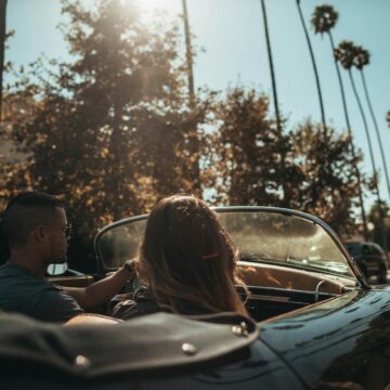 decapotable Un homme et une femme conduisant une décapotable classique sous le soleil de Los Angeles.
