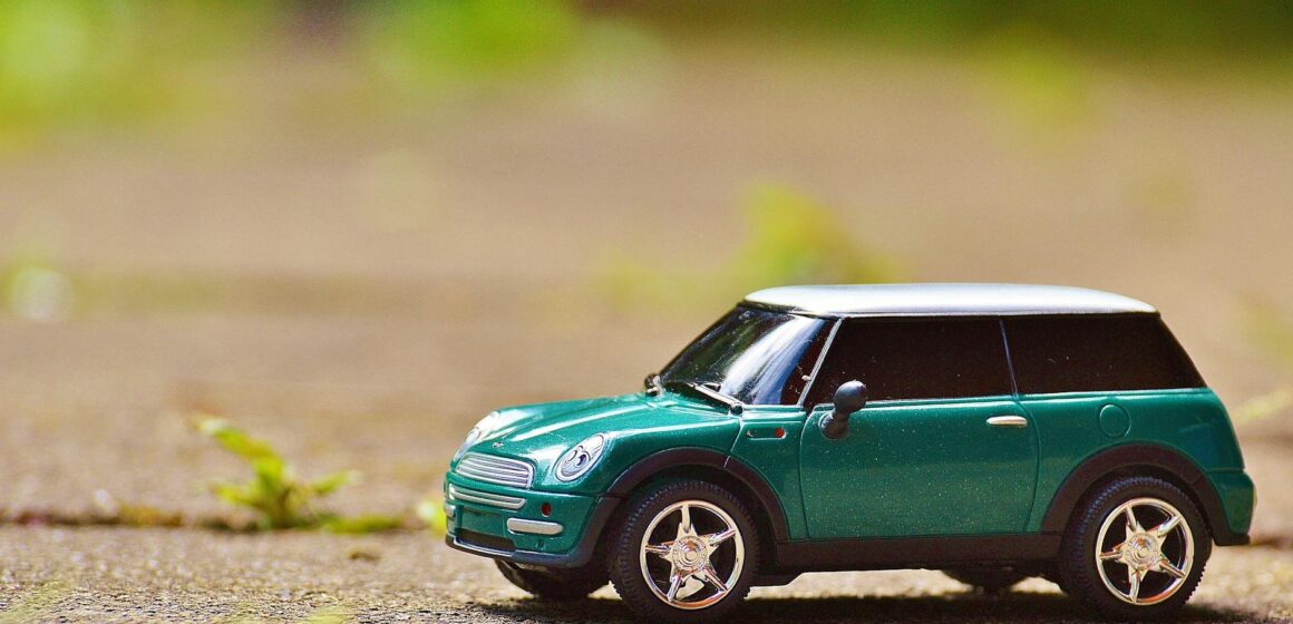 assurance-voiture Green Toy Mini Cooper Car sur le trottoir avec une profondeur peu profonde de champ à l'extérieur.