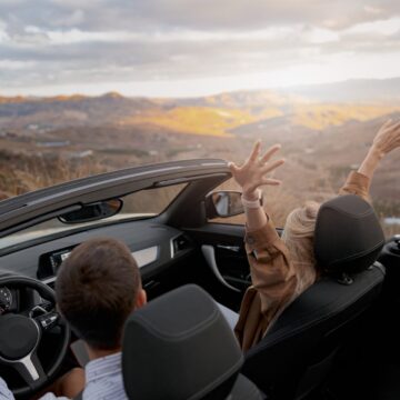 decapotable Arrière de couple homme et femme voyageant dans une voiture convertible à flanc de montagne profitant de la vue panorama