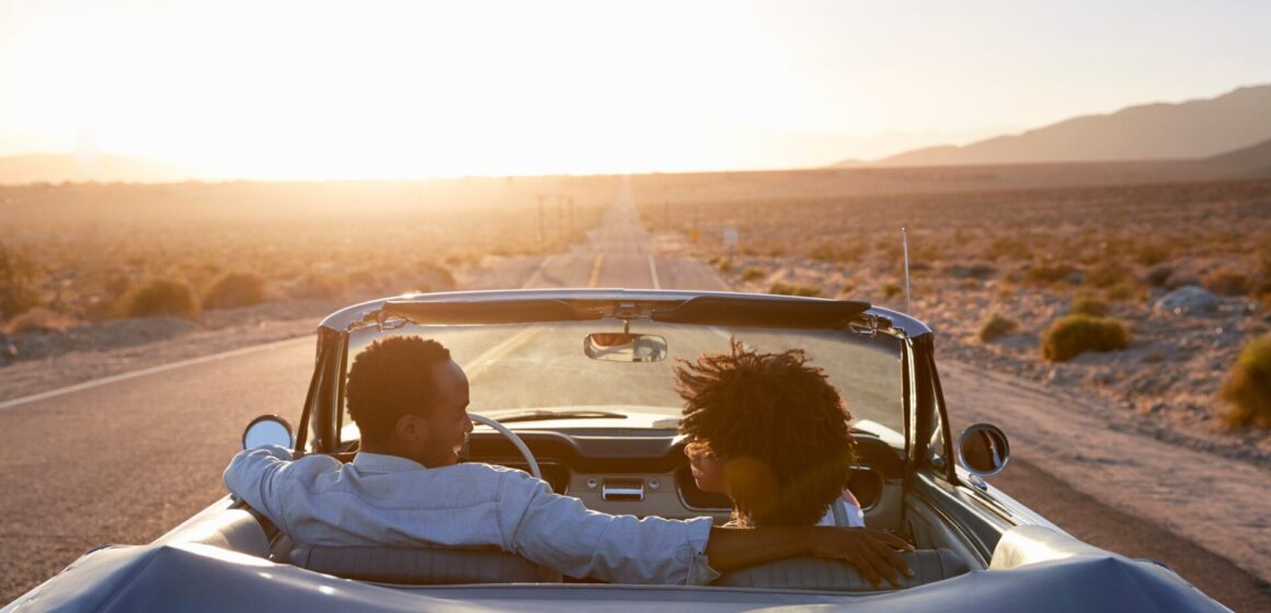 road-trip Vue arrière du couple sur road trip conduisant une voiture convertible classique vers le coucher du soleil