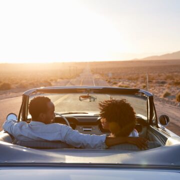 road-trip Vue arrière du couple sur road trip conduisant une voiture convertible classique vers le coucher du soleil