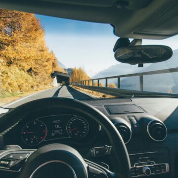 voiture Vue depuis l'intérieur de la voiture traversant une route de montagne pittoresque avec le feuillage d'automne et un ciel clair.