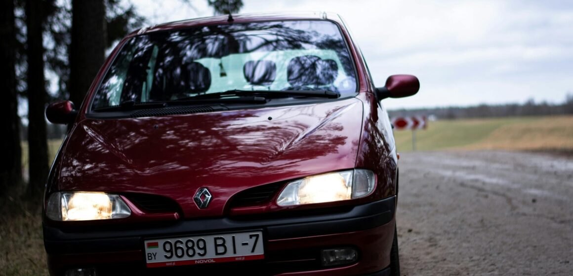 renault-scenic Gros plan d'un pittoresque Renault rouge sur une route rurale pendant la journée.