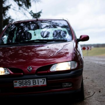 renault-scenic Gros plan d'un pittoresque Renault rouge sur une route rurale pendant la journée.
