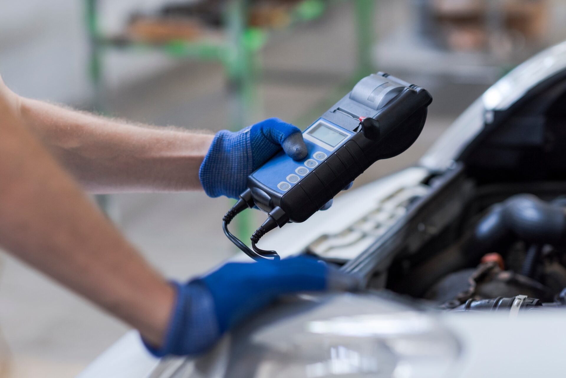 Mécanicien professionnel faisant une inspection de voiture, il utilise un testeur de batterie