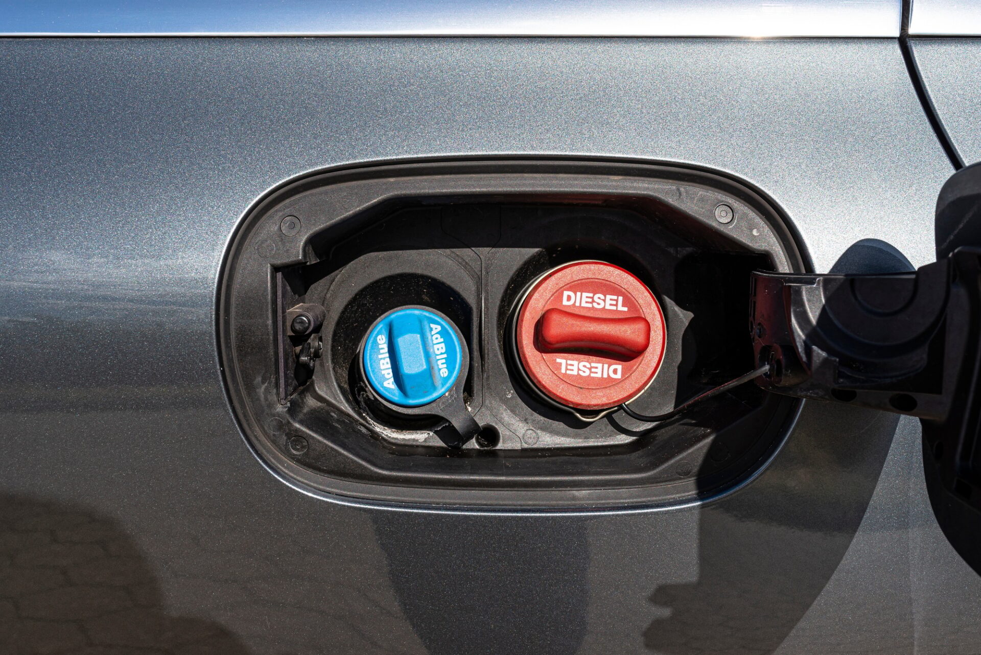 Volet de remplissage de carburant ouvert avec un capuchon diesel rouge et un AdBlue bleu, les bouchons de remplissage de carburant sont fermés.