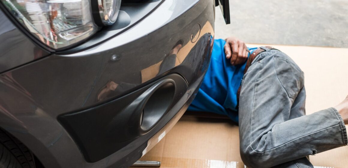 under-car Les travailleurs sont sous la voiture pour changer d'huile moteur