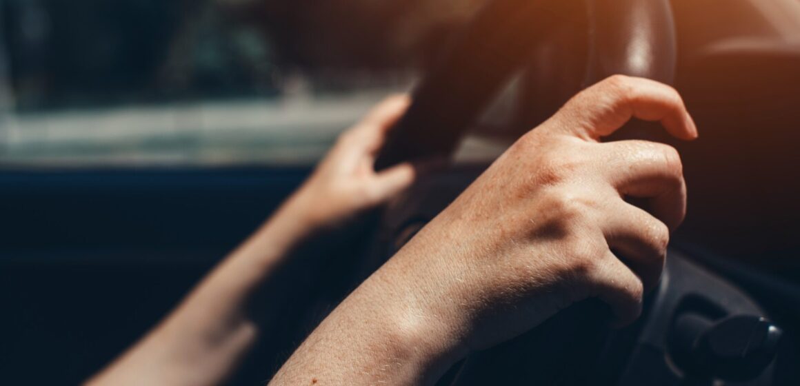 Steering-column-car Femme pratique sur le volant de la voiture, femme conduisant dans les rues de la ville le jour d'été ensoleillé