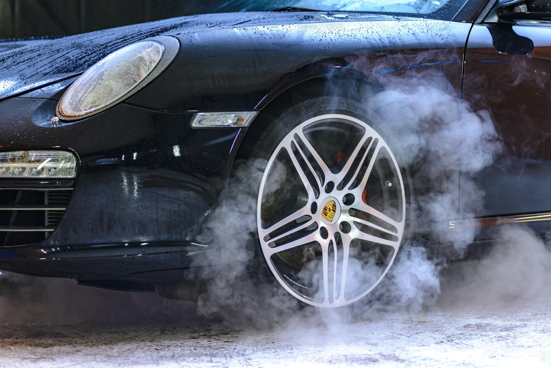 Gros plan d'une roue de voiture de luxe avec des gouttelettes de vapeur et d'eau, présentant de la puissance et du style.