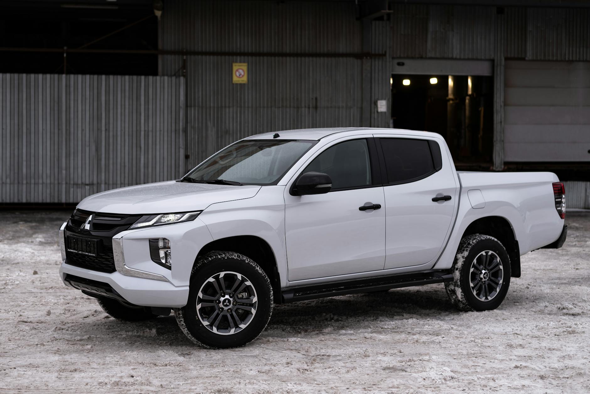 Camion de camionnette moderne Mitsubishi Garcée sur la neige, présentant un design élégant et des capacités prêtes pour l'hiver.