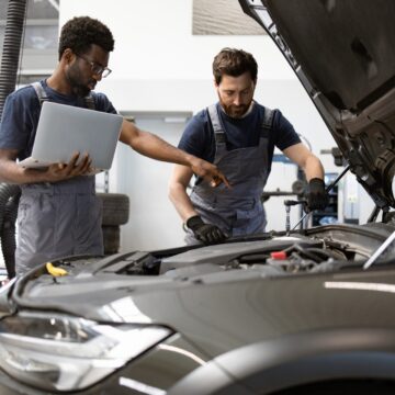 automotive-reliability Mécanique automatique travaillant sur la voiture dans le garage à l'aide d'un ordinateur portable pour les diagnostics.