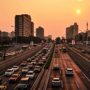 cars Une autoroute urbaine animée avec un trafic intense sous un ciel de coucher de soleil vibrant dans un fond de paysage urbain.