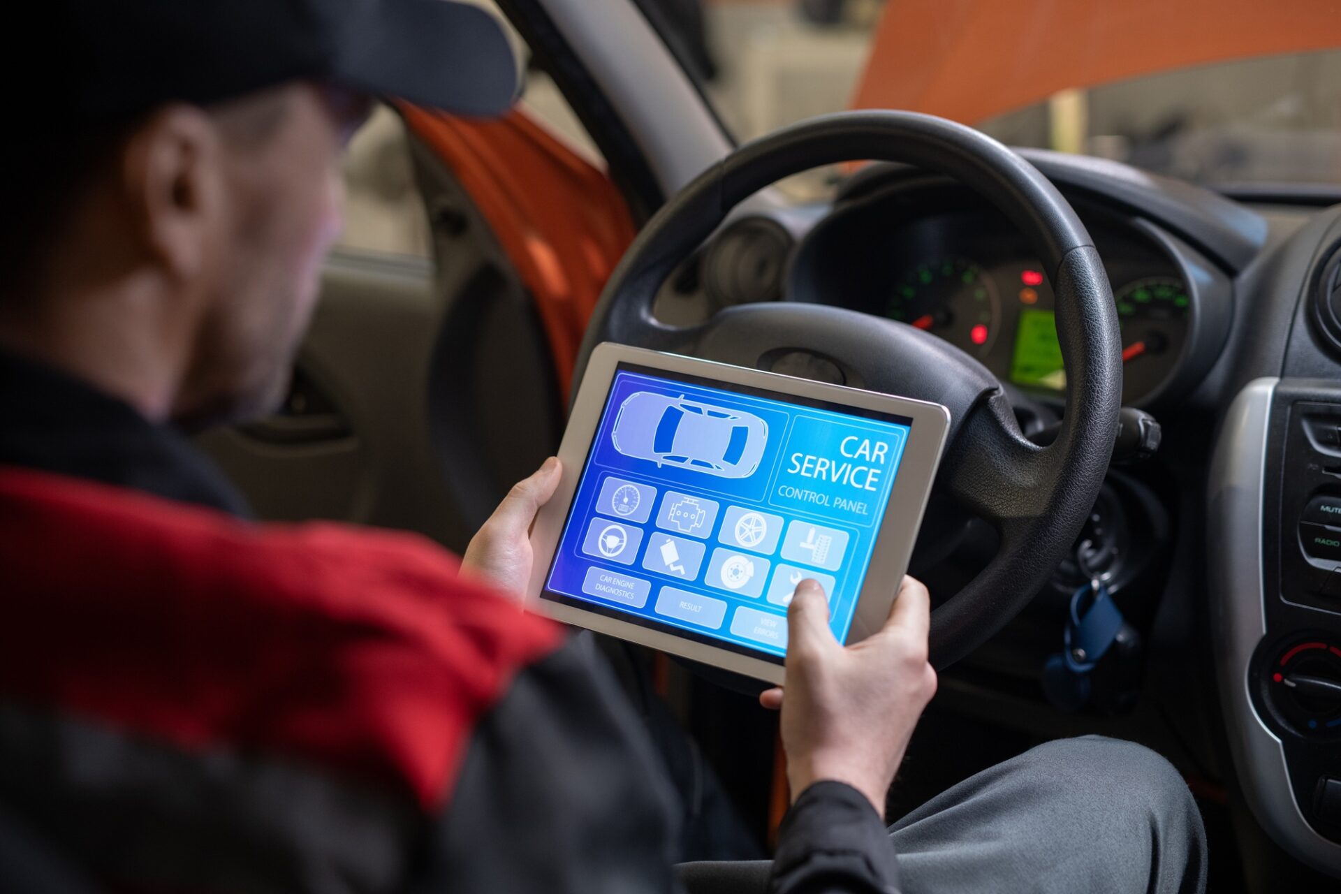 Gros plan du mécanicien de voiture à l'aide d'une tablette numérique avec application de service et de maintenance à l'écran lors de l'inspection des véhicules dans l'atelier de réparation automobile