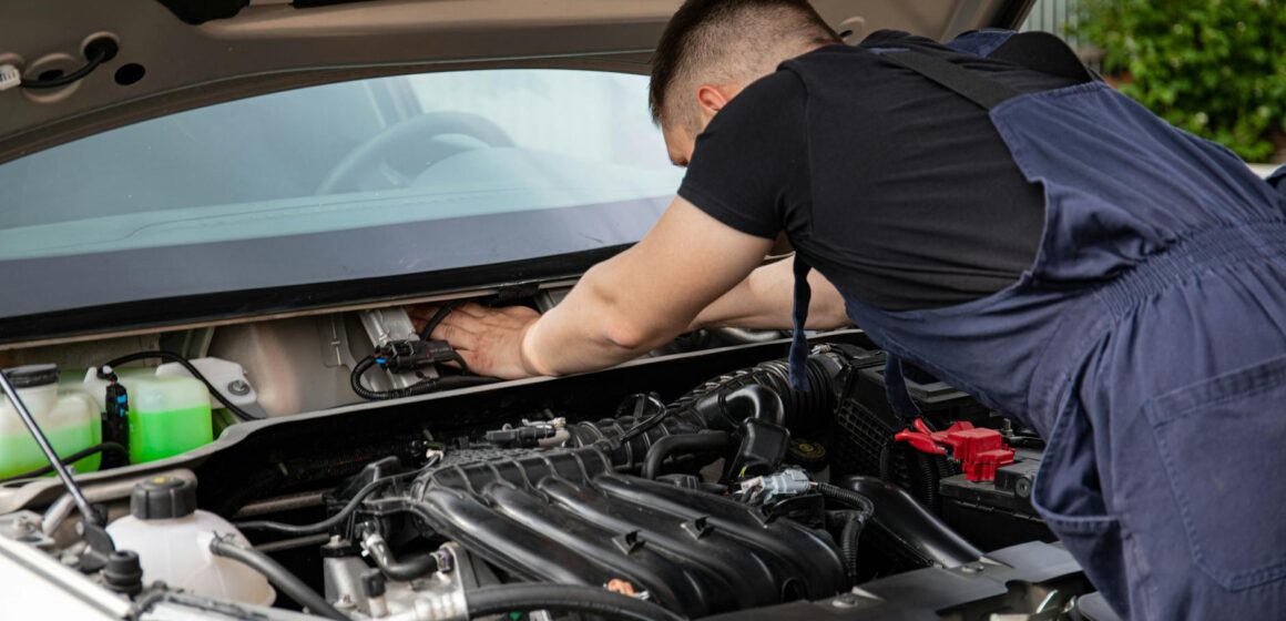 Garages Le mécanicien automobile effectue la maintenance du moteur sur une voiture.