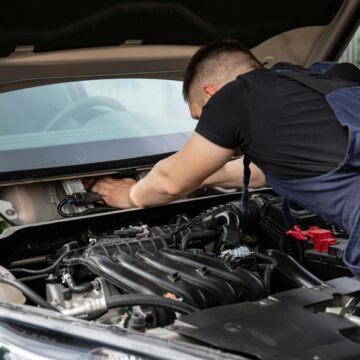 Garages Le mécanicien automobile effectue la maintenance du moteur sur une voiture.