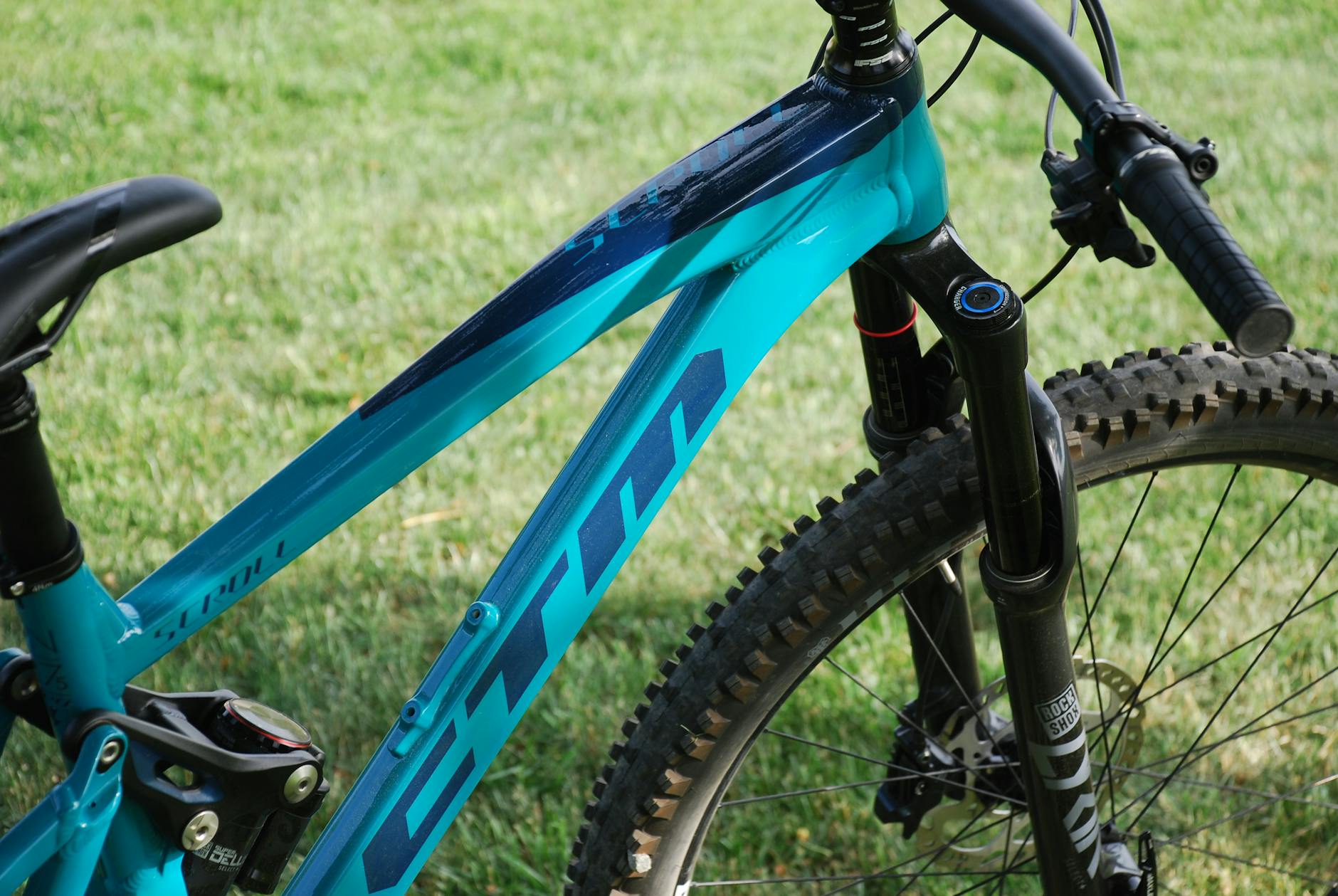 Gros plan détaillé d'un vélo de montagne bleu stationné sur l'herbe verte.
