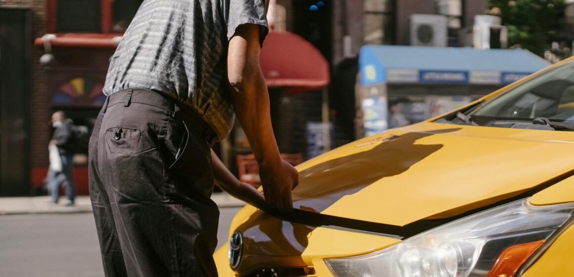 problem-auto Homme inspectant le capot ouvert d'un taxi jaune sur City Street.