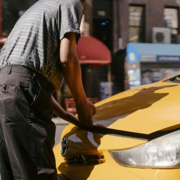 problem-auto Homme inspectant le capot ouvert d'un taxi jaune sur City Street.