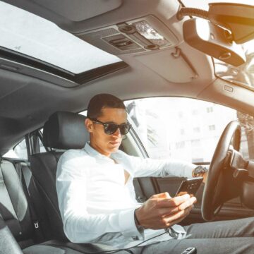 sunroof Un homme portant des lunettes de soleil sur son téléphone en conduisant une voiture au Maroc.
