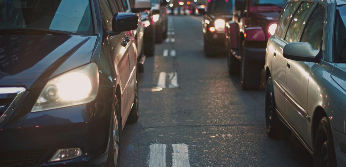 cars-2 Une rue encombrée bordée de voitures coincées dans la circulation au crépuscule, mettant en valeur la vie urbaine.