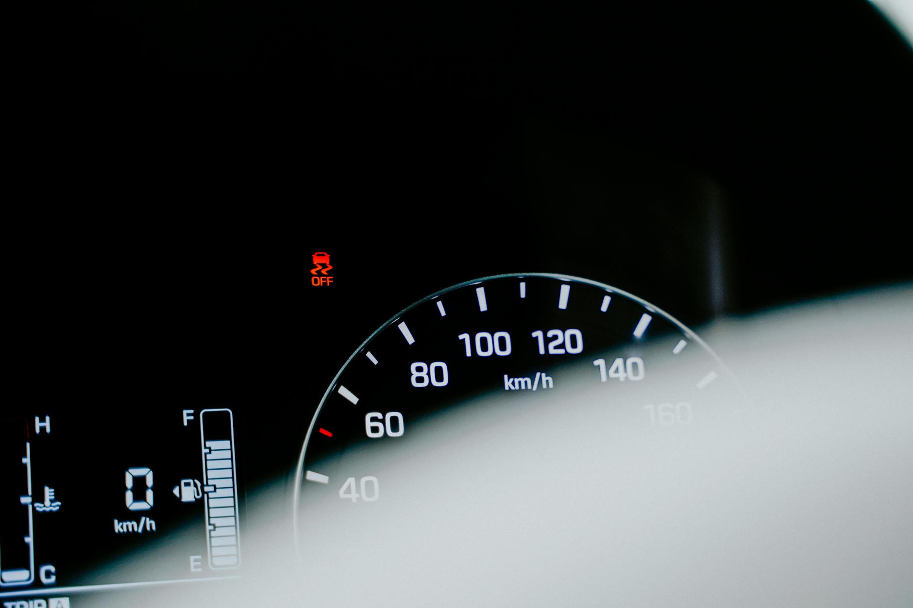Gros plan détaillé d'un compteur de vitesse de voiture affichant une lecture numérique et un voyant d'avertissement.