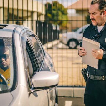 car-fine Agent de police à la fenêtre d'une voiture délivrant une contravention à un conducteur dans un cadre extérieur ensoleillé.