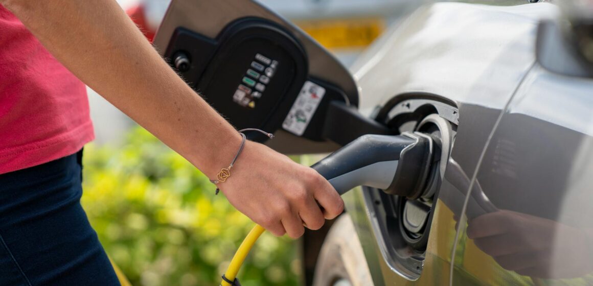 voiture-electrique Gros plan d'une personne branchant une voiture électrique à une borne de recharge à l'extérieur.