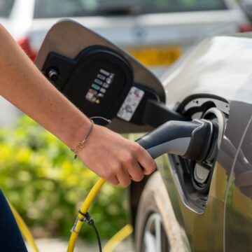 voiture-electrique Gros plan d'une personne branchant une voiture électrique à une borne de recharge à l'extérieur.