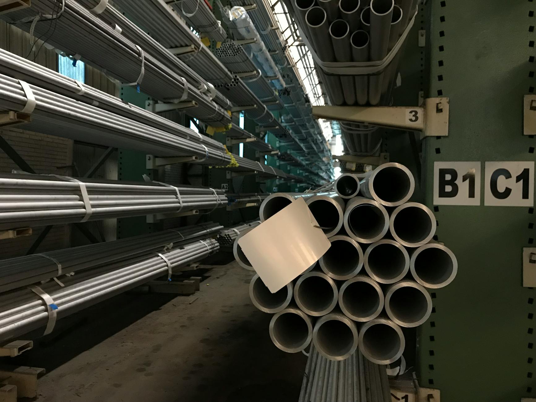 Rangées de tubes d'acier empilés dans un entrepôt industriel, présentant un stockage organisé.