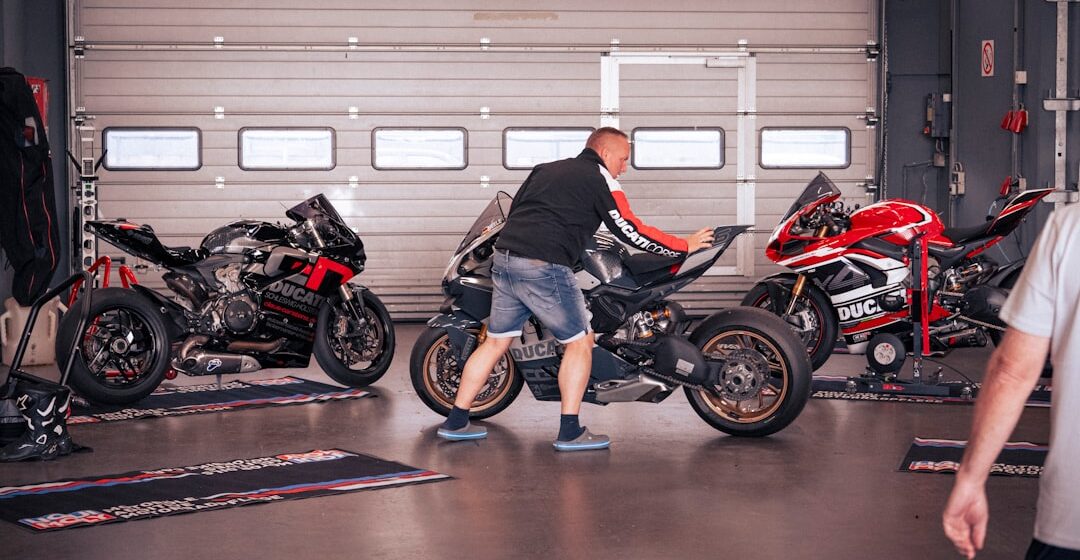 controle-technique-motos Un homme nettoie une moto dans un garage.