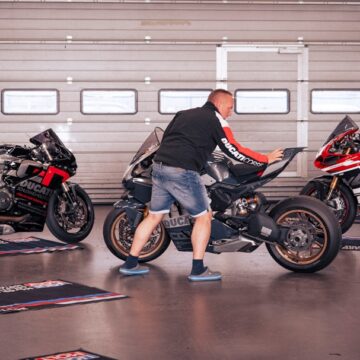 controle-technique-motos Un homme nettoie une moto dans un garage.